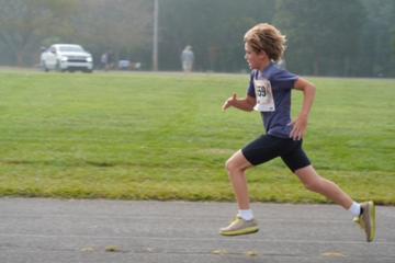A young runner sprinting across the grass at the Waynesville Recreation Center.