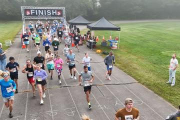 Runners crossing the finish line at the Rec Jam 5K on the Waynesville Recreation Center track.
